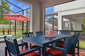 An outdoor patio with a table and chairs, a pool, and a view of a house. - Private Theater, Themed Rooms & Hot Tub (Davenport)
