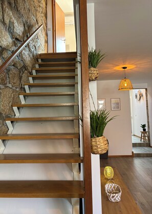 A staircase with wooden steps and a stone wall on one side. There are potted plants on the wall and a hanging light fixture. - Porto Terrace House | Private Terrace | Free Wi-Fi | by Constanjo Homes (Porto)