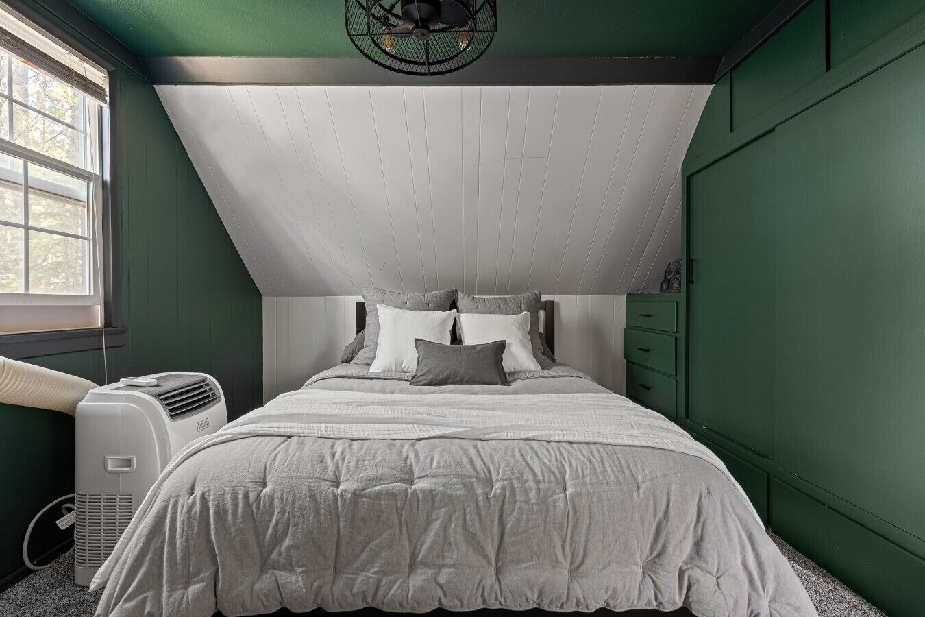 Ein Schlafzimmer mit Bett, Fenster und Wandklimaanlage.