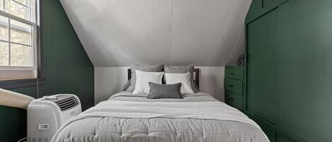 Ein Schlafzimmer mit Bett, Fenster und Wandklimaanlage.