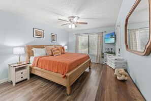 A bedroom with a bed, bedside tables, a ceiling fan, a TV, and a large mirror. - W Hyde Pk 19B in Kingston 1st floor, Pool, Beach (Myrtle Beach)