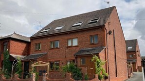 A two-story brick house with a pitched roof, a front porch, and a small garden area. - Hotel Jacks Court (Ashton-under-Lyne)