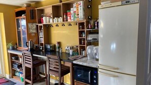 A kitchen with wooden cabinets, a white refrigerator, and a microwave. - Hotel Jacks Court (Ashton-under-Lyne)