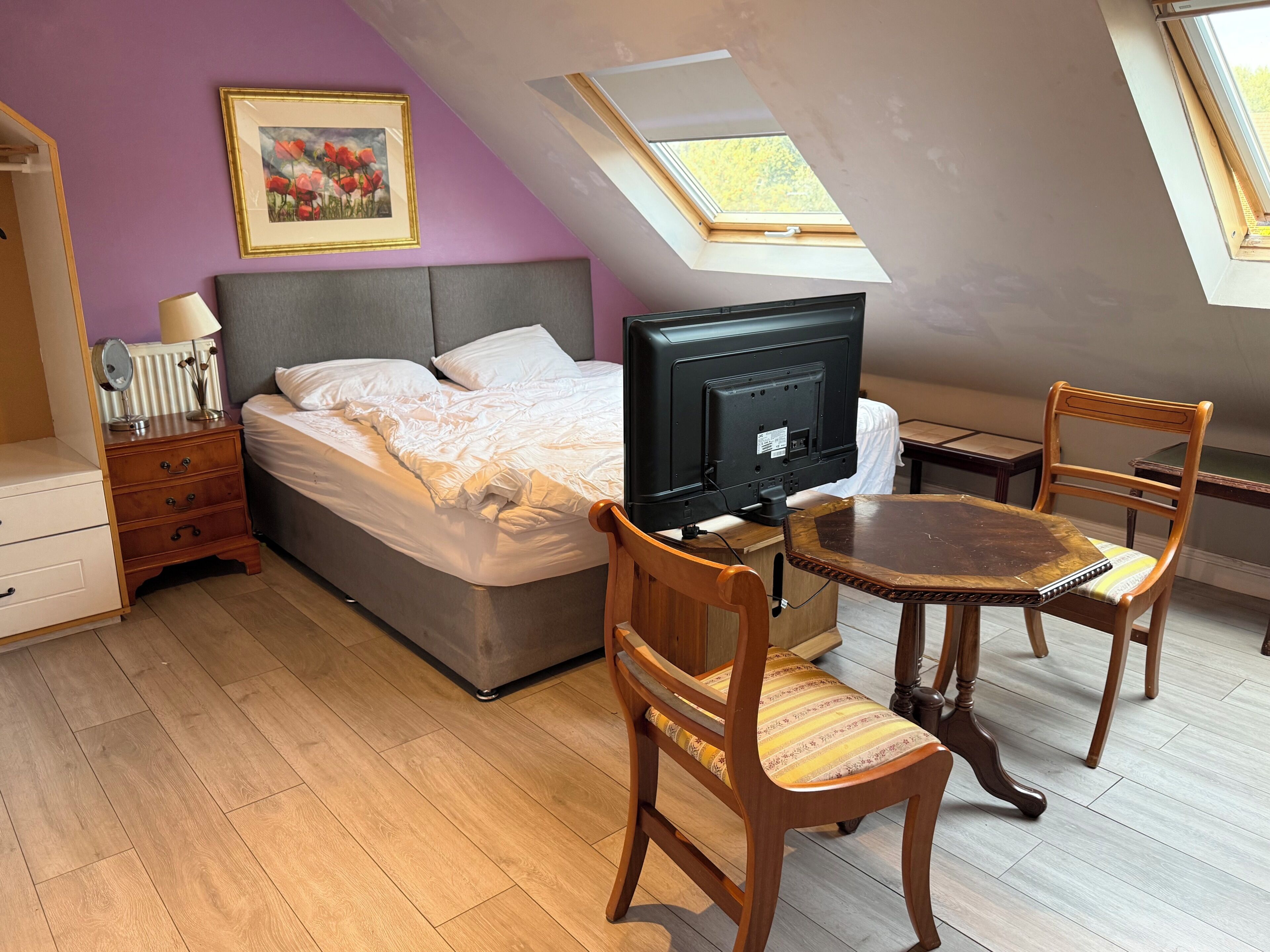 A bedroom with a bed, a television, a desk, and a chair.