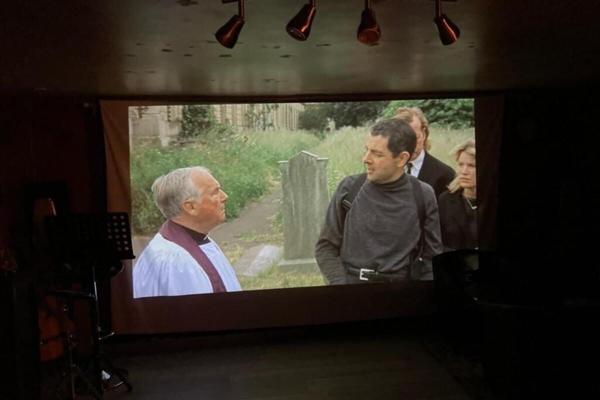 A projection screen with a scene of people outdoors.