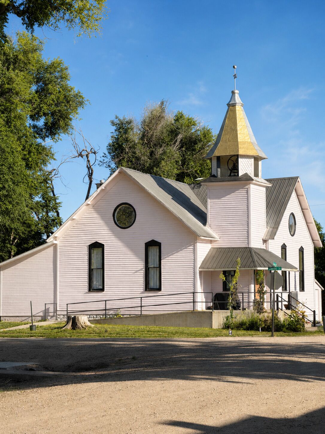 A church with a steeple, a bell tower, and a front porch.