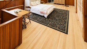 Een slaapkamer met een bed, bureau, stoel, kledingkast en plafondventilator.