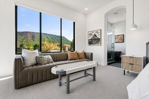 A modern bedroom with a large window, a sofa, a bedside table, and a bed. - Sedona Single-Level · Remodeled, Two Kings, Red Rock Views, Tennis, Pool & Golf (Sedona)