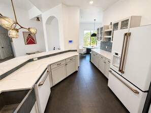 Eine moderne Küche mit weißen Schränken, einer Marmorarbeitsplatte und einem integrierten Kühlschrank.
