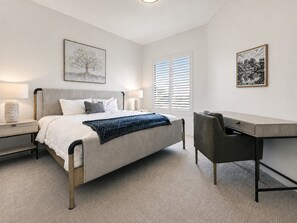 Ein Schlafzimmer mit Bett, Nachttischen, einem Schreibtisch und Stühlen.