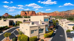 A residential area with modern houses, a curved road, and a mountain range in the background. - Sedona Single-Level · Remodeled, Two Kings, Red Rock Views, Tennis, Pool & Golf (Sedona)