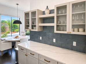 A modern kitchen with white cabinetry, dark tiled backsplash, and a view of greenery outside. - Sedona Single-Level · Remodeled, Two Kings, Red Rock Views, Tennis, Pool & Golf (Sedona)