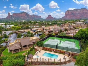 A residential area with a tennis court, swimming pool, and houses with a mountainous backdrop. - Sedona Single-Level · Remodeled, Two Kings, Red Rock Views, Tennis, Pool & Golf (Sedona)
