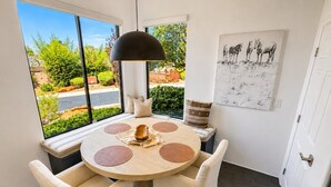 A dining area with a round table, four chairs, a pendant light, and a view of greenery outside. - Sedona Single-Level · Remodeled, Two Kings, Red Rock Views, Tennis, Pool & Golf (Sedona)