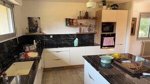 Une cuisine moderne avec des plans de travail en marbre noir, des meubles blancs et un four encastré.