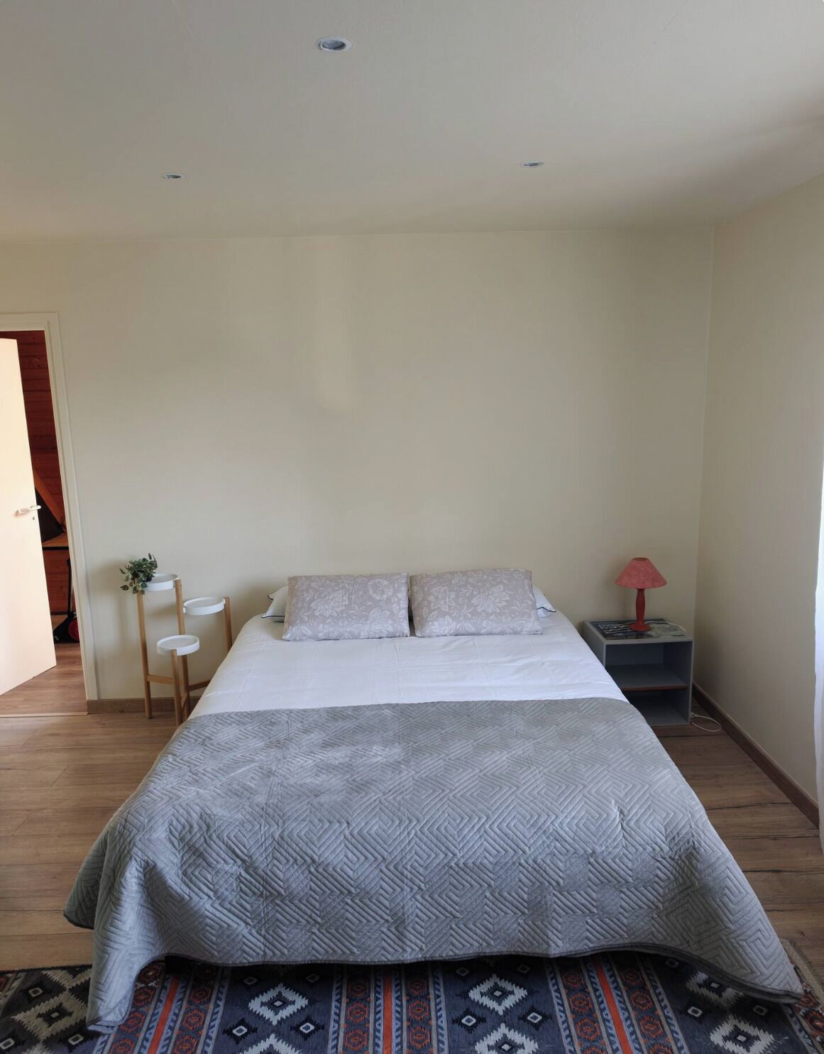 A bedroom with a bed, bedside tables, a lamp, and a patterned rug.