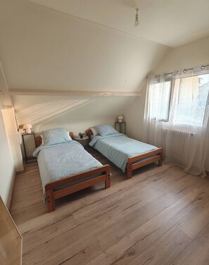 Um quarto com duas camas de madeira, uma mesa pequena e um abajur.