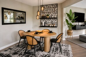 Un coin repas avec une table ronde, quatre chaises et une décoration murale sur le thème du café.