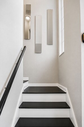 A staircase with white walls and black steps, leading to a landing with a door and a light fixture. - Luxury Townhome 15 min to Disney Universal Orlando (Davenport)