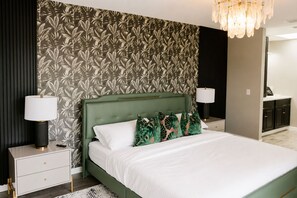 A modern bedroom with a green upholstered headboard, white bedding, and a floral wallpaper design. - Luxury Townhome 15 min to Disney Universal Orlando (Davenport)