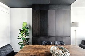 Un comedor moderno con una mesa de madera, sillas tapizadas en negro y una planta grande.