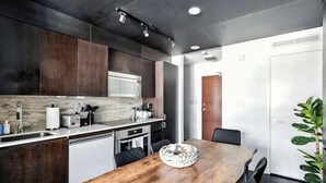 Une cuisine moderne avec des meubles de rangement en bois foncé, une table à manger en bois et un réfrigérateur blanc.