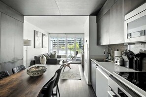 A modern kitchen with a dining area, large windows, and a view of a residential building. - CityPlace Skyline Retreat Sleeps 5 w Patio! (Toronto)