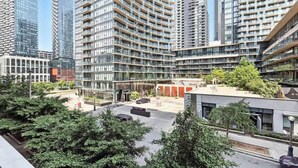 Un immeuble résidentiel de grande hauteur doté de nombreux balcons, d’un espace de stationnement et entouré de verdure.