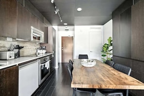 A modern kitchen with a wooden dining table and chairs, a built-in oven, and a microwave. - CityPlace Skyline Retreat Sleeps 5 w Patio! (Toronto)