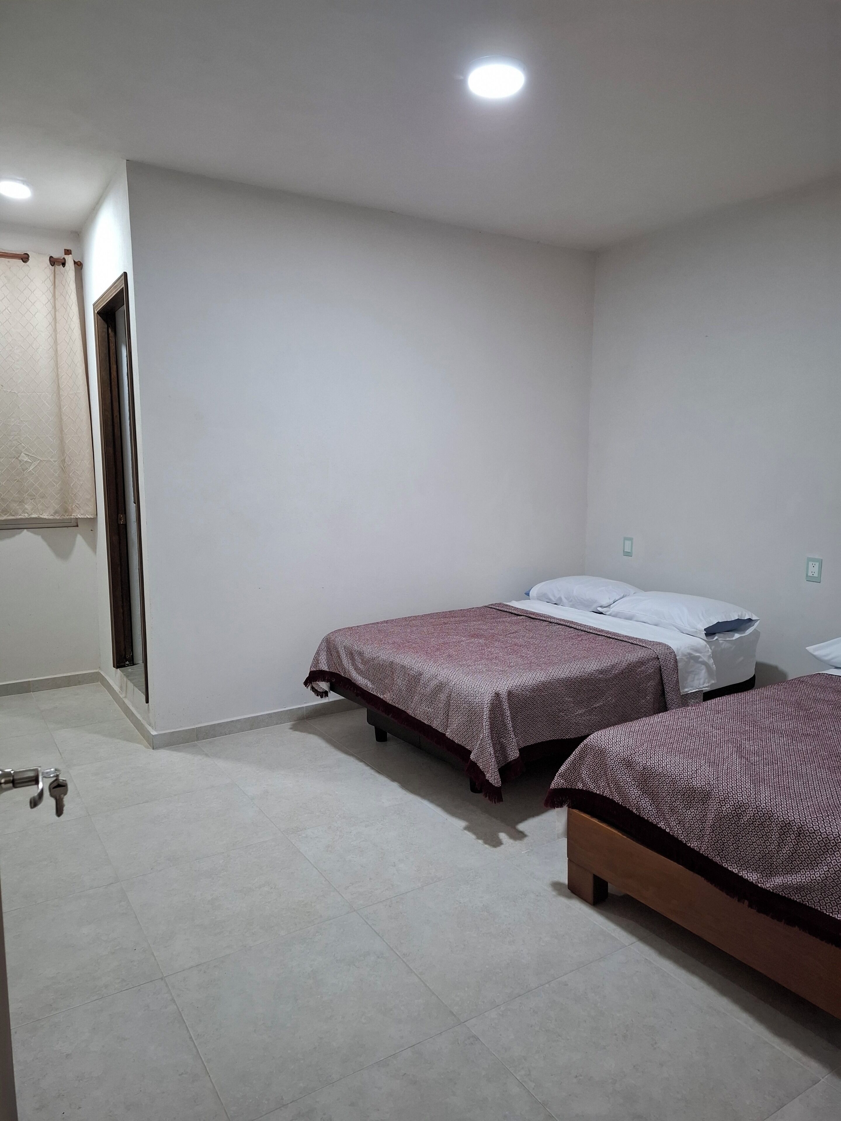 Una habitación con dos camas, una puerta y una lámpara.