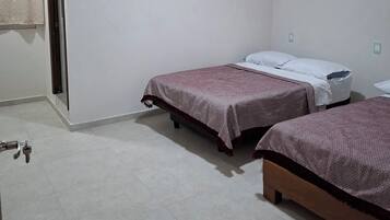 Una habitación con dos camas, una puerta y una lámpara.