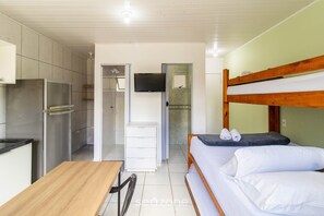 A compact room with a bunk bed, a kitchenette, a TV, and a small desk. - Studio in Floripa, Minutes From the Beach Flt0011 (Florianópolis)
