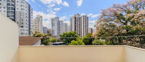 Un balcón con vista a la ciudad, con edificios altos y flores de cerezo.
