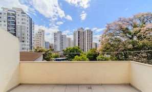 A balcony with a cityscape view, including high-rise buildings and cherry blossoms. - Studio in Floripa, Minutes From the Beach Flt0011 (Florianópolis)