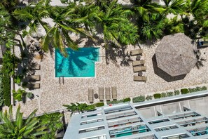 An aerial view of a resort with a swimming pool, lounge chairs, and palm trees. - Siesta Sands - Unit 512 (Siesta Key)