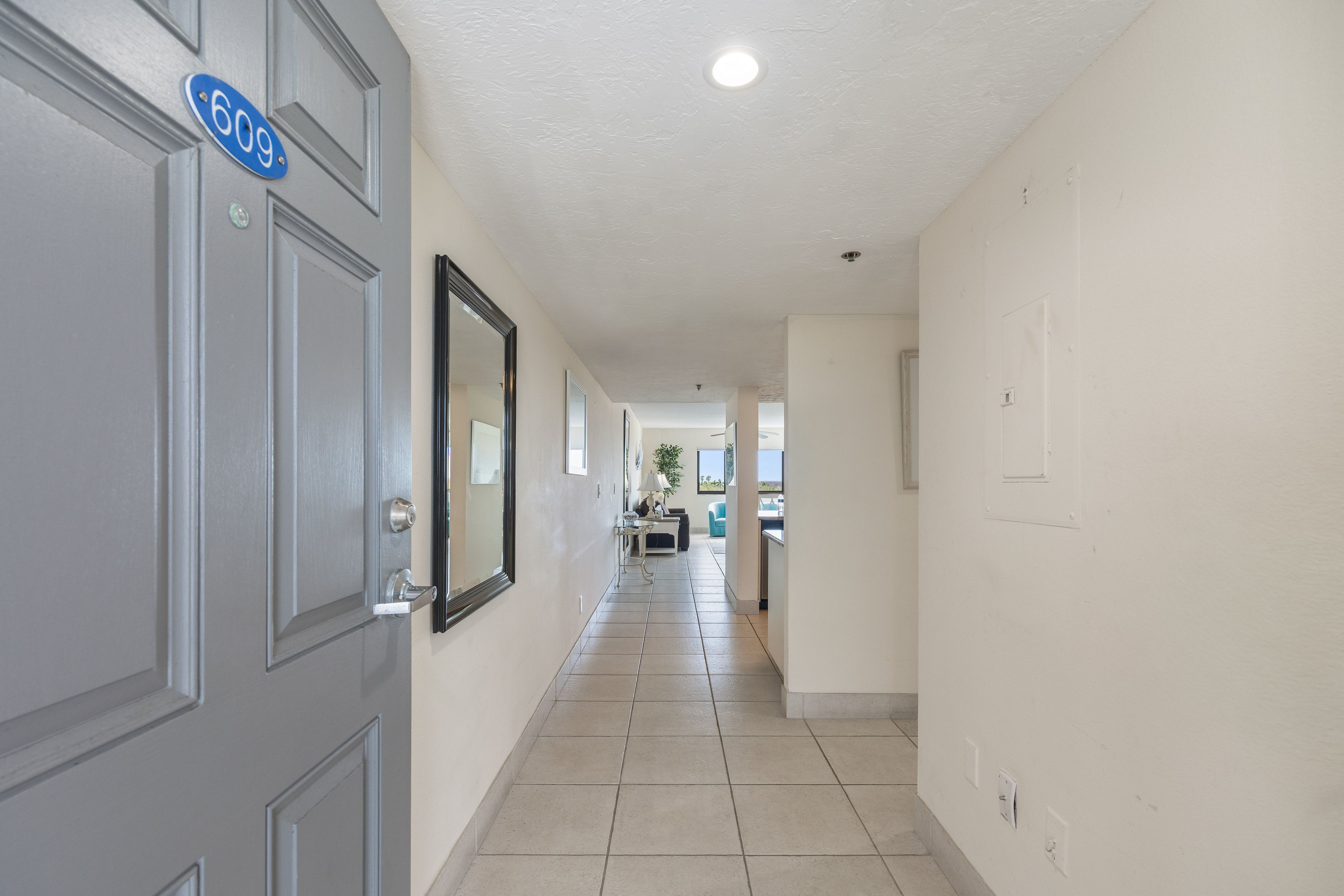 A hallway with a door marked '609', a mirror, and a view into a room with a dining area.