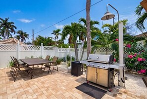 An outdoor patio with a grill, dining table, chairs, and a white fence. - Siesta Sands Unit 308 (Siesta Key)
