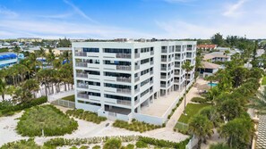 A multi-story hotel with balconies, a pool area, and surrounding greenery. - Siesta Sands Unit 308 (Siesta Key)