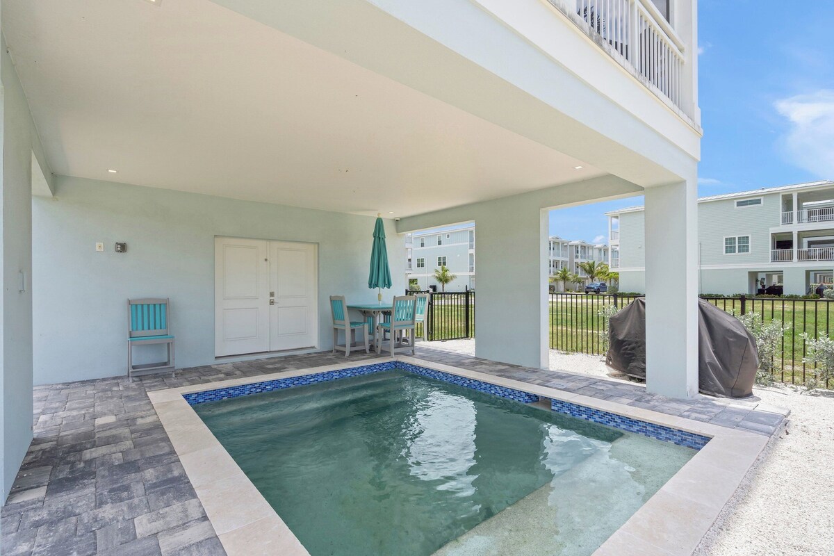 A covered swimming pool with a tiled edge, a door, and a bench.