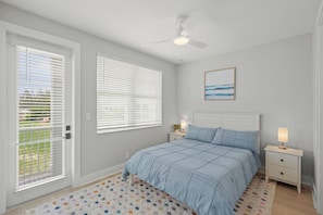 A bedroom with a bed, bedside tables, a ceiling fan, and a view of the outdoors through the window. - Hunters Point Resort and Marina Mainsail (Cortez)