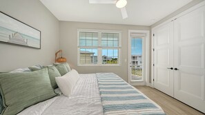 A bedroom with a bed, a window with blinds, a door, and a ceiling fan. - Hunters Point Resort and Marina Mainsail (Cortez)