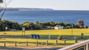 A coastal park with a bench, picnic tables, and a sign indicating 'WHARF'. - Belle Mer - Bega Street 4 Tathra (Tathra)