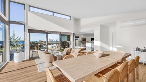 Ein modernes Interieur mit einem großen Esstisch, bequemen Sitzgelegenheiten und Blick ins Freie.
