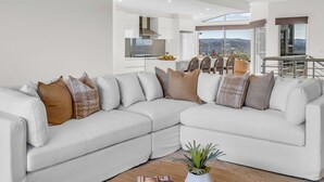 Ein modernes Wohnzimmer mit einem Ecksofa, einem Couchtisch und Blick auf die Küche und den Essbereich.