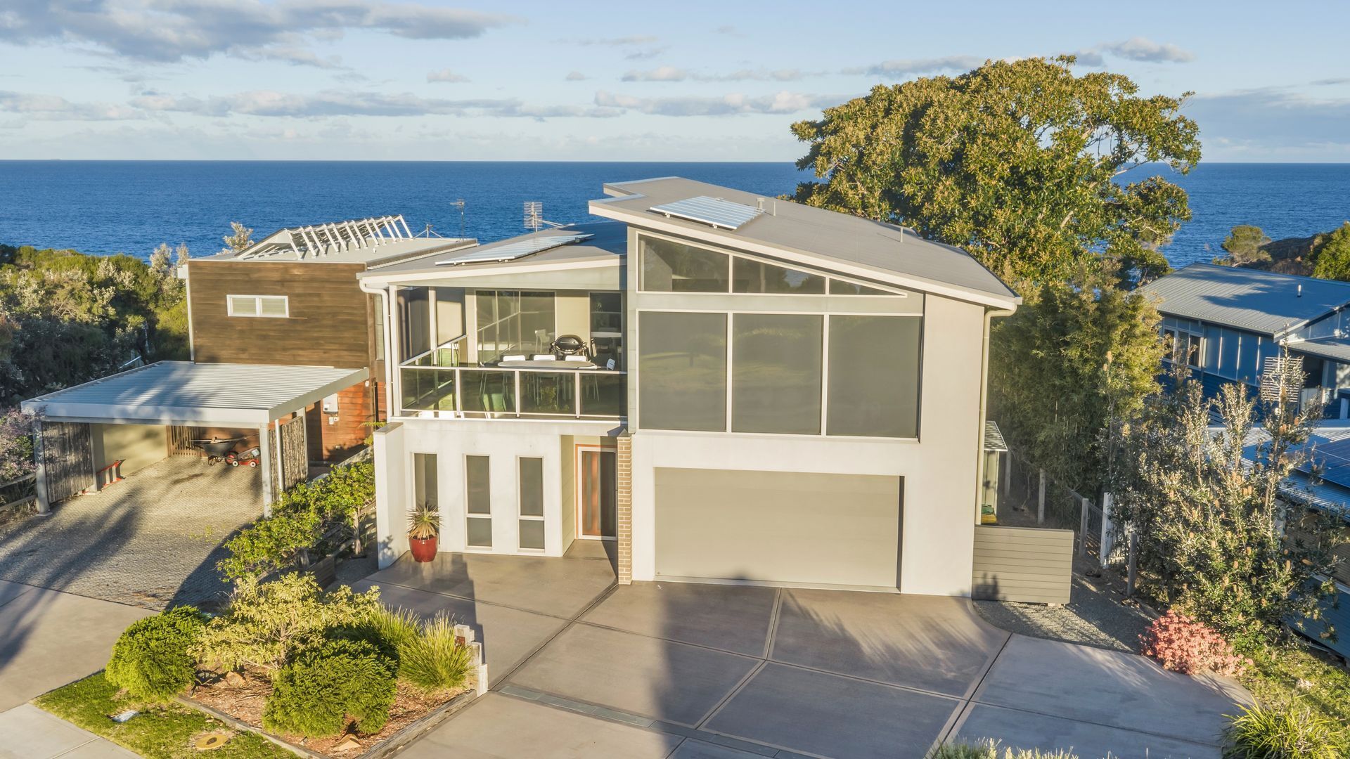 Una casa moderna de dos pisos con garaje, un patio cubierto y vista al mar.