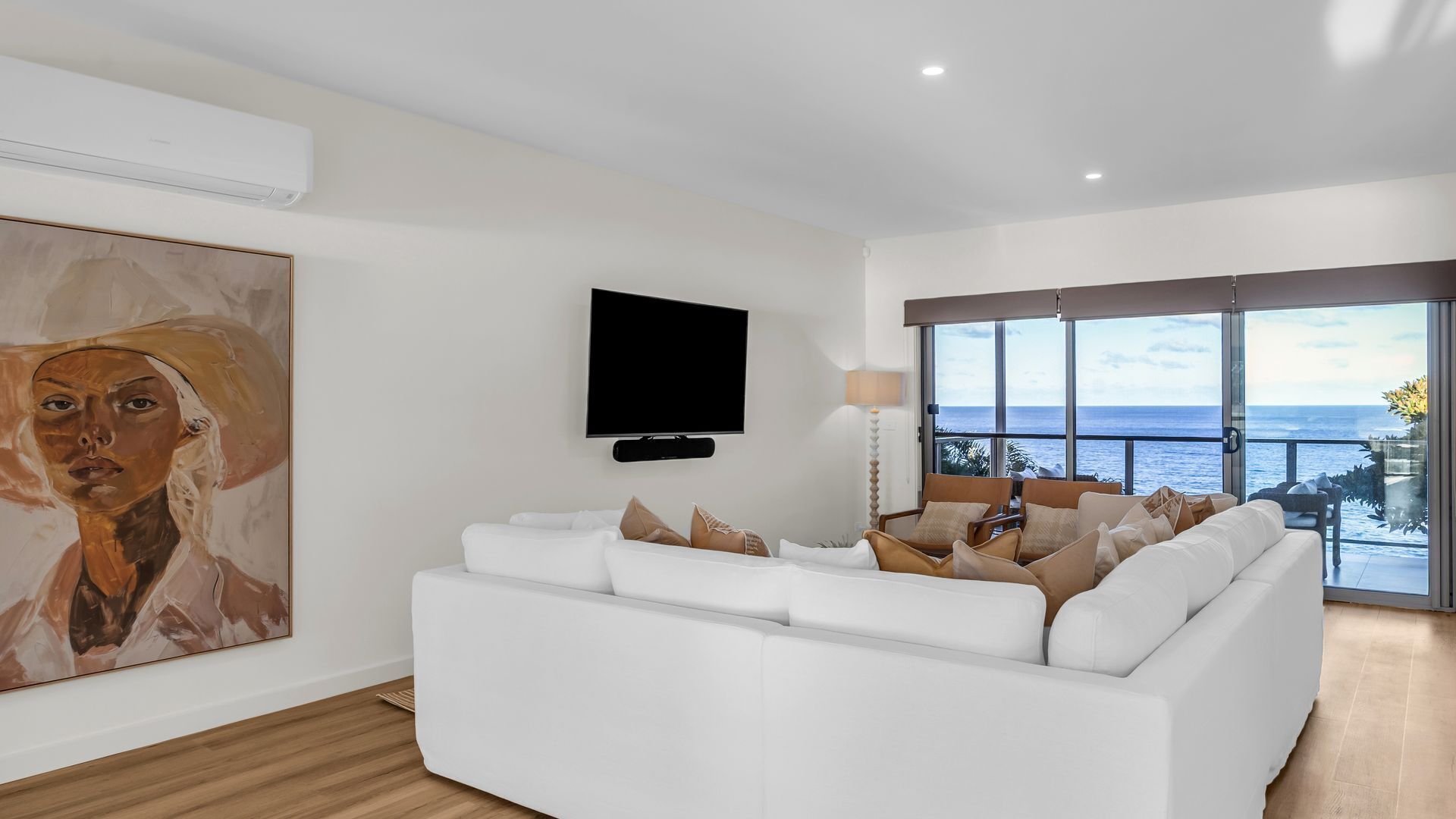 Ein modernes Wohnzimmer mit einem weißen Sofa, einem Flachbildfernseher und einem großen Gemälde an der Wand.