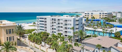 A resort with multiple buildings, a pool area, and a beach view.