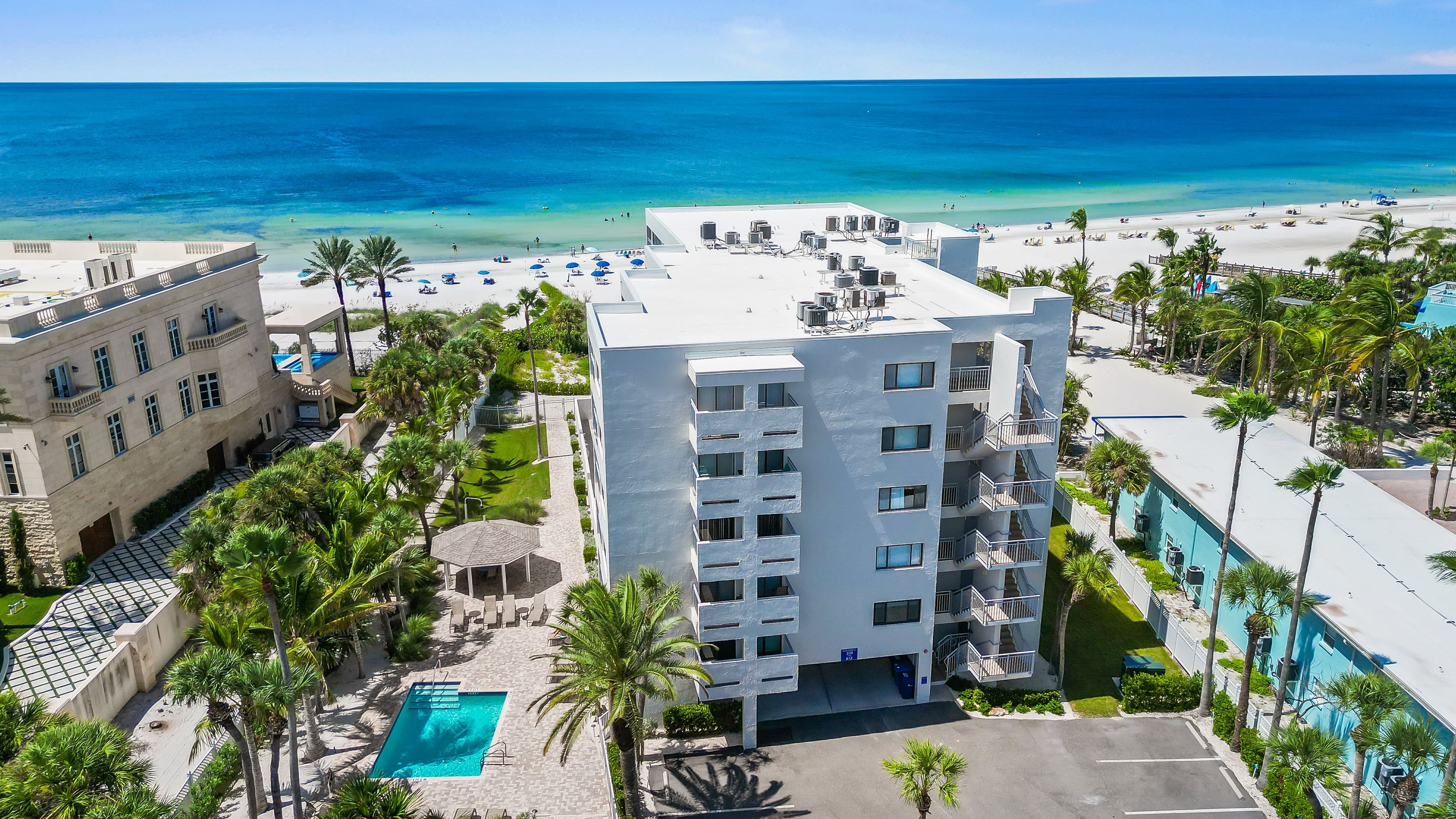 A hotel with a pool, beachfront view, and multiple balconies.