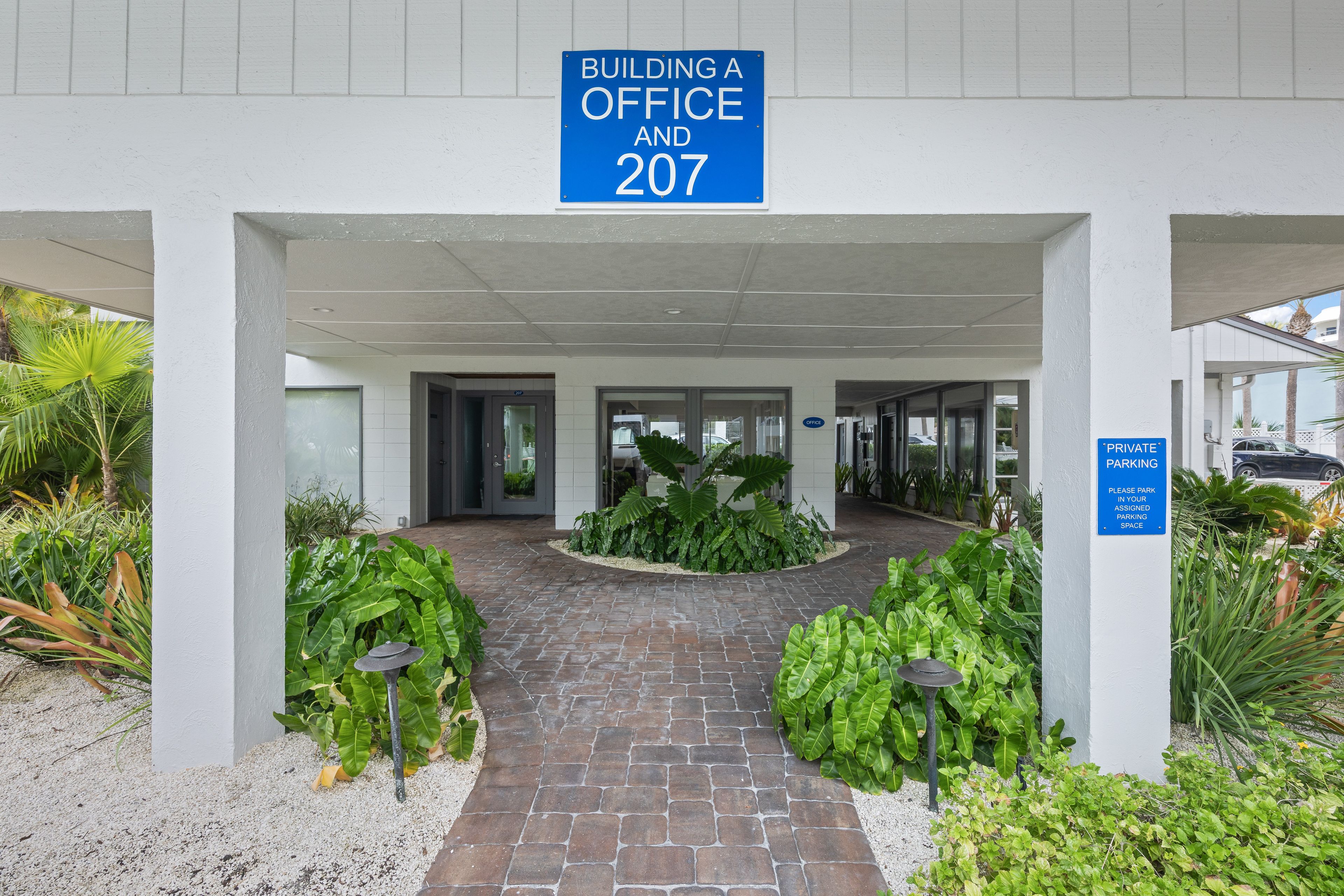 Entrada d'un edifici amb un senyal que indica 'BUILDING A OFFICE AND 207'.