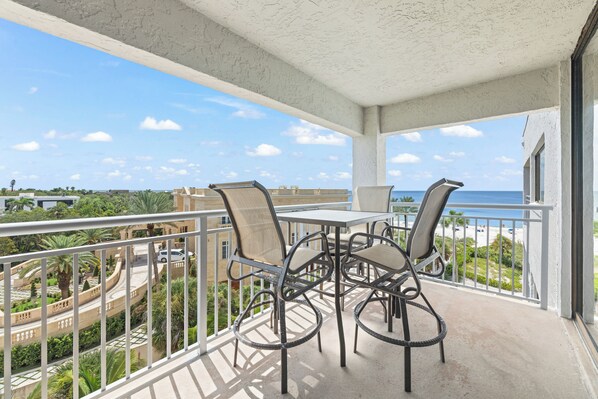 Un balcon avec une table et des chaises, donnant sur une plage et offrant une vue sur la ville.